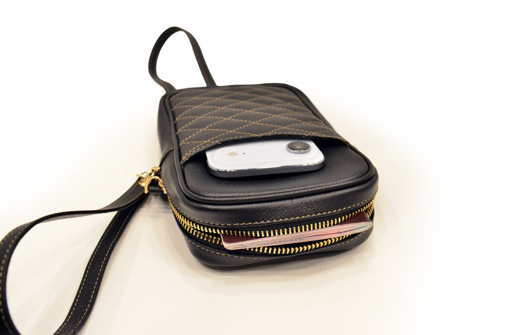 Studio photo of the camel leather passport holder with a phone in its front pocket and the gold zip open