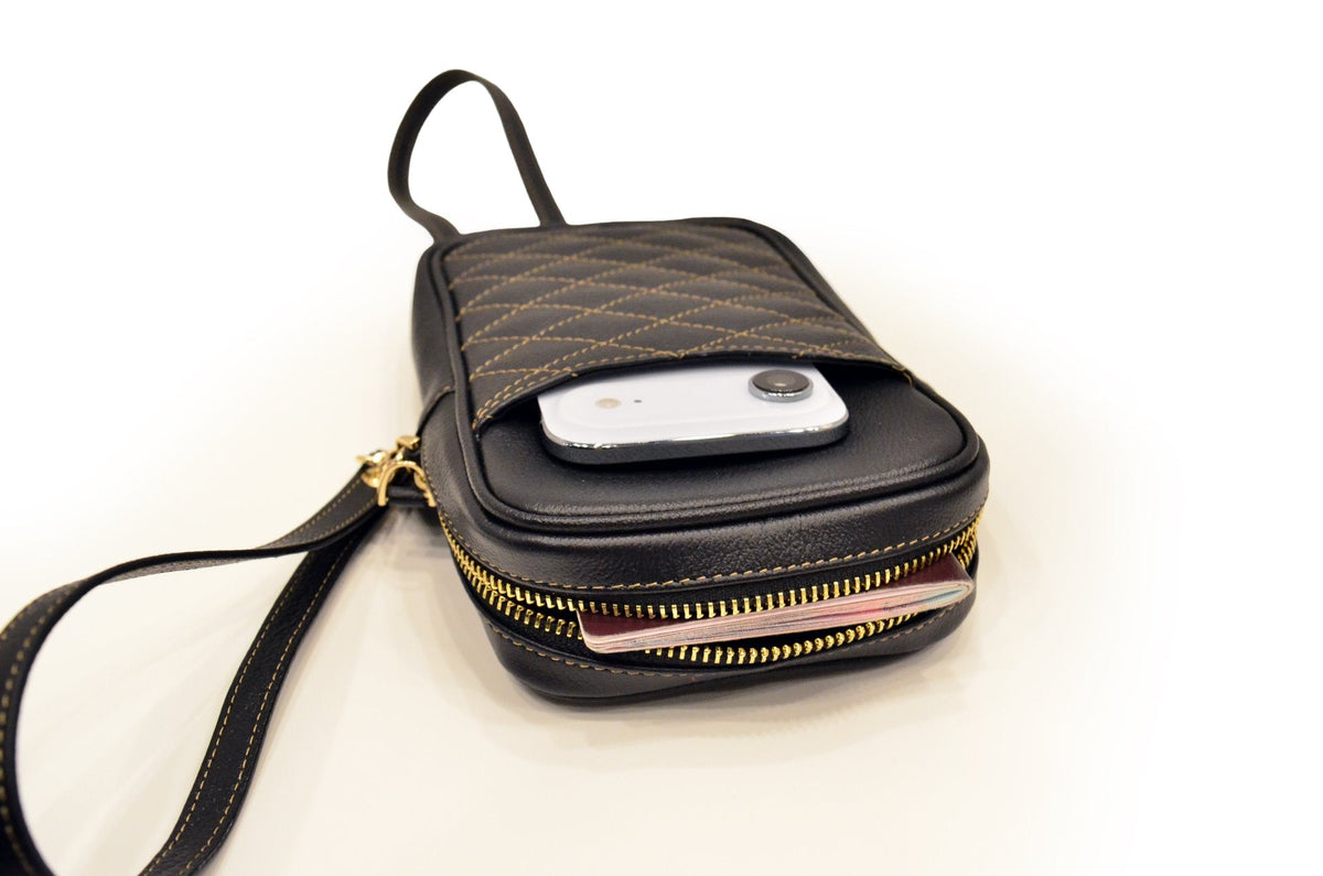 Studio photo of the camel leather passport holder with a phone in its front pocket and the gold zip open