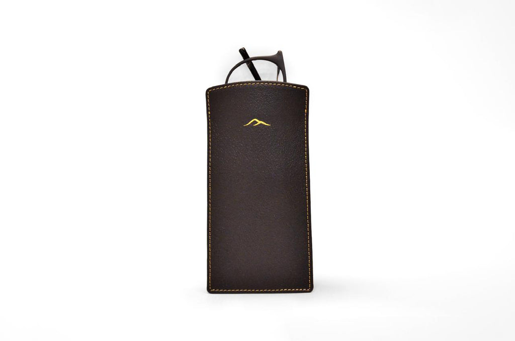 Studio photo of the black camel leather eyeglasses pouch with glasses sliding inside, showing the gold logo